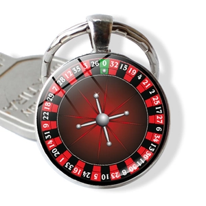 Roulette wheel keychain pendant with glass cabochon and silver alloy frame next to a key