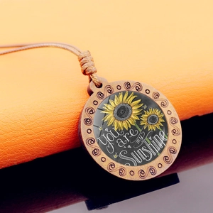 Macro detail van houten zonnebloem hanger met de tekst You are my Sunshine gegraveerd