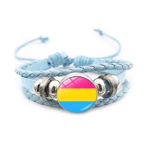 Dettaglio del bracciale in pelle intrecciata azzurra con ciondolo bandiera pansexual