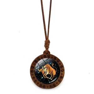 Handcrafted wooden zodiac necklace with gold Taurus sign on a blue galaxy background