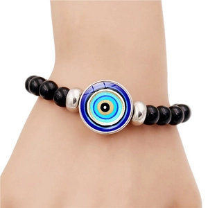 Bracelet œil bleu avec perles noires et détails argentés porté sur le poignet