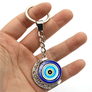 Crescent moon Turkish Evil Eye keychain with silver vine pattern held by hand