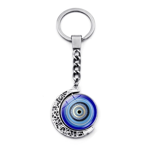 Macro view of rotating silver moon keychain featuring a blue evil eye glass nazar charm