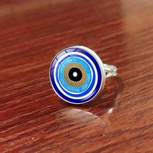 Macro shot of silver evil eye ring featuring blue concentric circles on wooden texture
