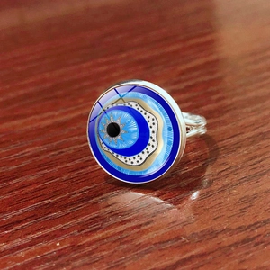 Adjustable silver Turkish Evil Eye talisman ring on a rustic dark wood surface