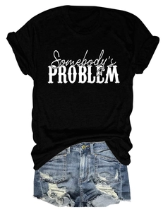 Détail du t-shirt noir Somebody's Problem et short en jean bleu délavé avec franges