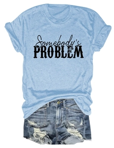 Détail du t-shirt bleu clair avec texte Somebody's Problem et short en jean