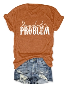 Détail d'un t-shirt orange avec imprimé et d'un short en jean court au look déchiré