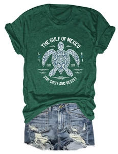 Détail d'un t-shirt vert foncé avec imprimé tortue et texte Gulf of Mexico sur fond blanc