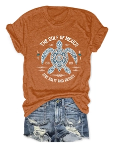 Détail du t-shirt orange brique avec imprimé tortue et short en jean effiloché