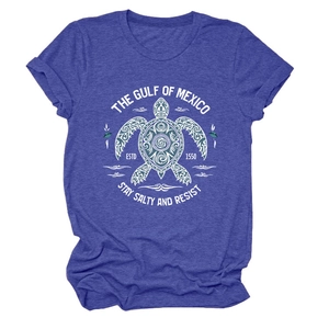 Détail d'un t-shirt bleu chiné avec imprimé tortue tribale blanche et texte côtier