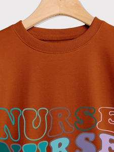Detailed view of the ribbed crew neck and colorful NURSE print on a brown sweatshirt
