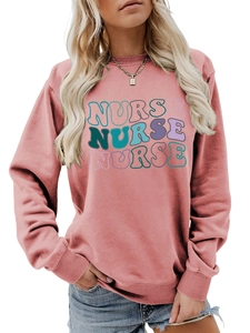 Close-up of pink crewneck sweatshirt with colorful retro NURSE wavy text print detail