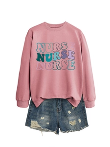 Detail of dusty pink nurse sweatshirt with colorful layered text and denim shorts