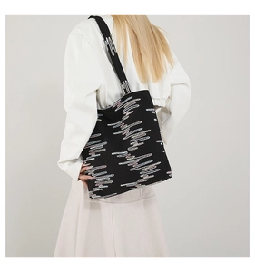 Detail of a black canvas tote bag with colorful gradient wave embroidery and wide strap