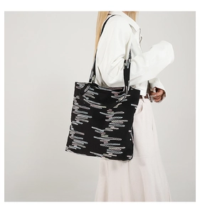 Close-up of a large tote bag featuring vibrant colorful wave patterns on black fabric