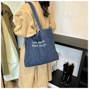 Detail of navy denim tote bag featuring white embroidery and large capacity for daily use