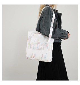 Detailed shot of white tote bag with colorful embroidery styled with denim jacket