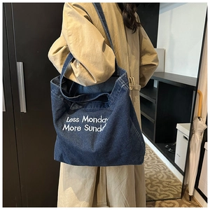 Detail of blue denim tote bag with white Less Monday More Sunday slogan print