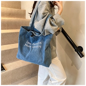 Dettaglio della borsa tote in denim blu con slogan Less Mondays More Sundays ricamato