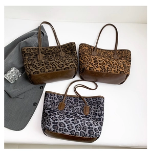 Three leopard print tote bags with brown leather handles displayed on a grey blazer