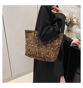 Side view of leopard print tote bag with brown leather trim carried by a model