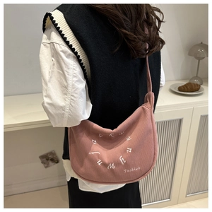 Détail du sac bandoulière en velours côtelé rose avec broderie de lettres blanches