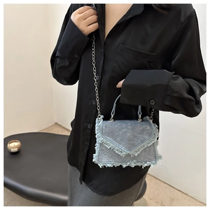 Detail of light blue denim mini bag showing frayed edges and silver chain strap
