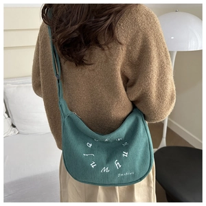 Détail du sac cabas en velours côtelé vert montrant la broderie et la bandoulière réglable