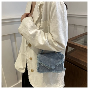 Detail der Vintage-Jeanstasche in Blau mit ausgefransten Kanten und silberner Kette