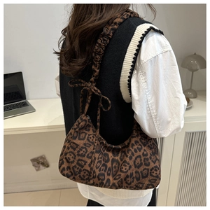 Detail of leopard print hobo shoulder bag with pleated strap and bow design on model