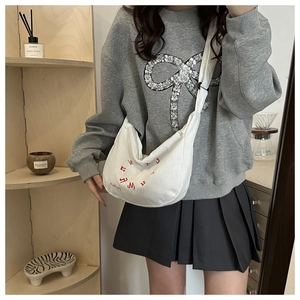 Détail du sac hobo en velours côtelé blanc avec broderie rouge et texture douce