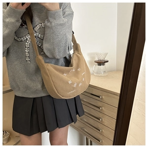 Détail du sac hobo en velours côtelé kaki avec broderie de lettres et large bandoulière