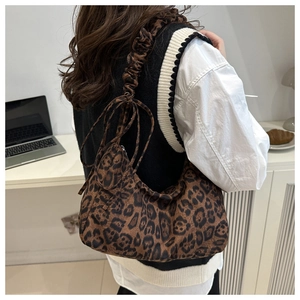 Detail of leopard print hobo bag featuring a scrunchie strap and round charm pouch
