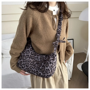 Detail of purple leopard print underarm bag with pleated shoulder strap and bow accent