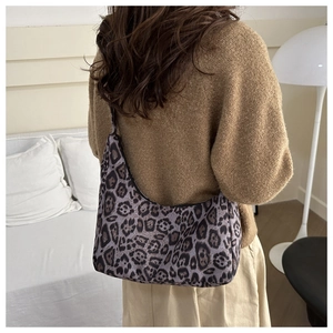 Detailed close-up of a leopard print canvas hobo bag worn by a model in a cozy room