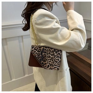 Detail of leopard print crossbody bag with gold chain strap on a white corduroy blazer