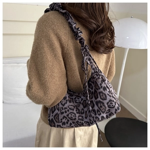 Detail of leopard print shoulder bag with ruched strap style shown on a model