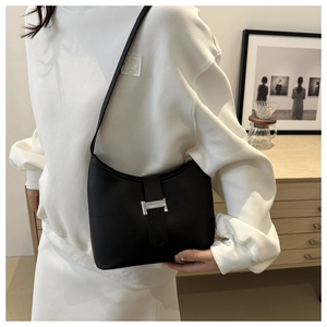 Close-up of minimalist black matte leather half-moon bag with silver H-buckle detail