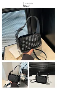 Detail view of black leather crossbody bag featuring silver studs and metal chain strap