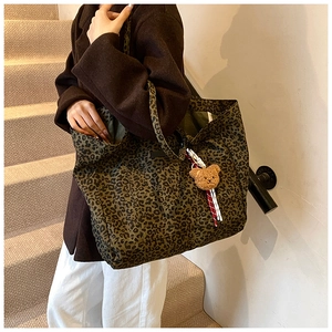 Leopard print tote bag shown on shoulder with brown teddy bear charm on stairs
