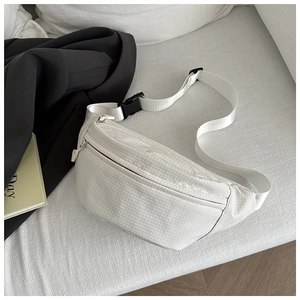 Detail of white nylon crossbody bag with grid pattern texture and black buckle strap