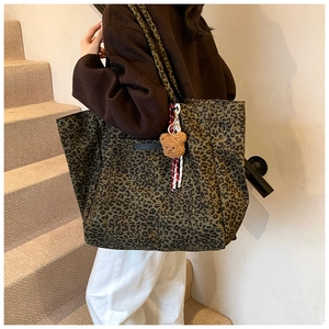 Detail of leopard print canvas tote bag with a cute brown bear plush charm and rope