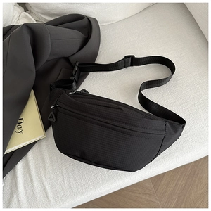 Detail of black nylon ripstop crossbody bag featuring dual zippers and adjustable strap buckle