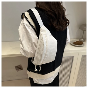 Close-up of white waffle texture sling bag with dual zippers and adjustable strap