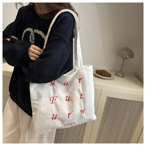 Détail du sac fourre-tout en velours côtelé blanc avec texture côtelée et broderie rouge