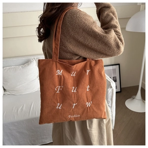 Détail de la broderie de lettres sur un sac cabas en velours côtelé orange