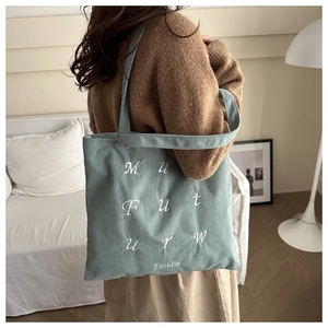Détail du sac fourre-tout en velours côtelé bleu clair avec broderie sur fond chaleureux