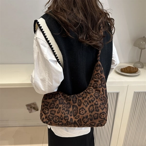 Chic leopard print hobo shoulder bag with a crescent shape worn by a model in a studio