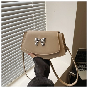 Detail of beige PU leather shoulder bag with a silver bow metal clasp and flip-top design